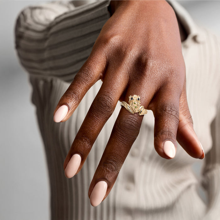 Gold frog ring worn on finger with blue and green stone details