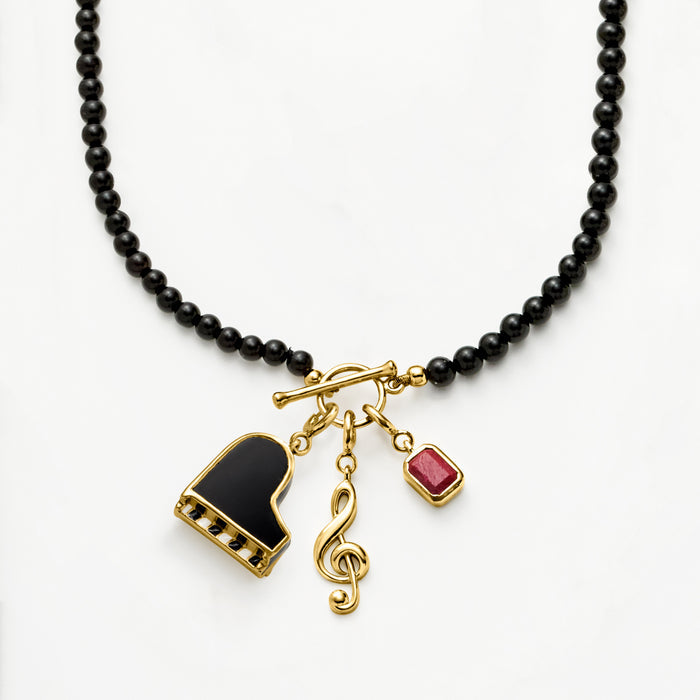Black bead necklace with gold treble clef charm and small red accent charm