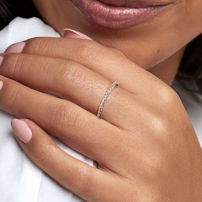 White gold roped ring on finger, close-up of twisted band texture