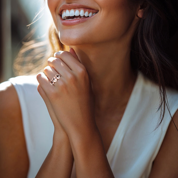 Rose gold ring on finger with three oval pink stones and small white side stones