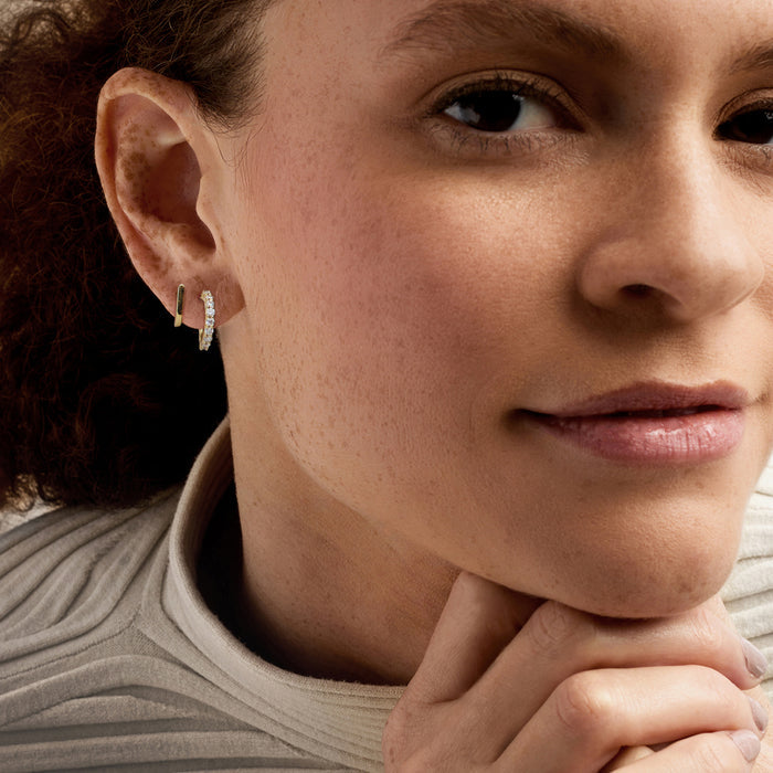 Gold double-hoop diamond earrings worn on ear, small stones on outer hoop