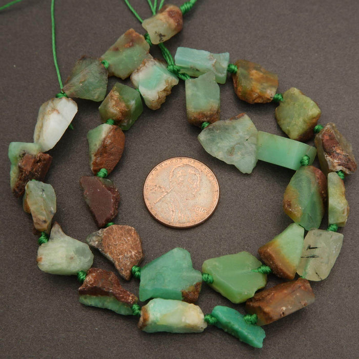 Necklace with green and brown beads next to a penny on a brown background