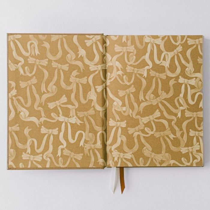 Notebook by Good Juju with gold detailing depicting a bow.