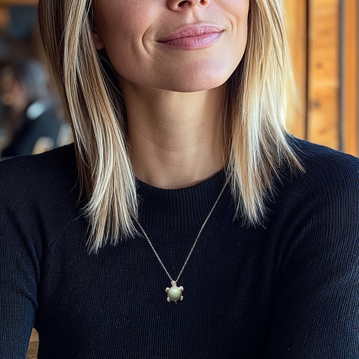Turtle pendant necklace worn by model: sterling silver chain with jade green gemstone