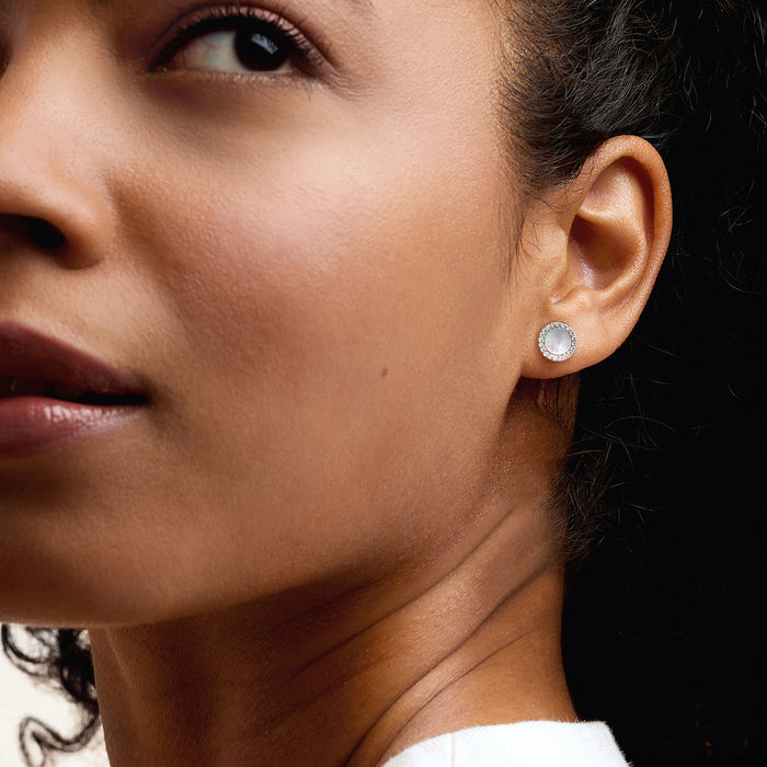 Sterling silver stud earrings with round mother-of-pearl and CZ halo on model