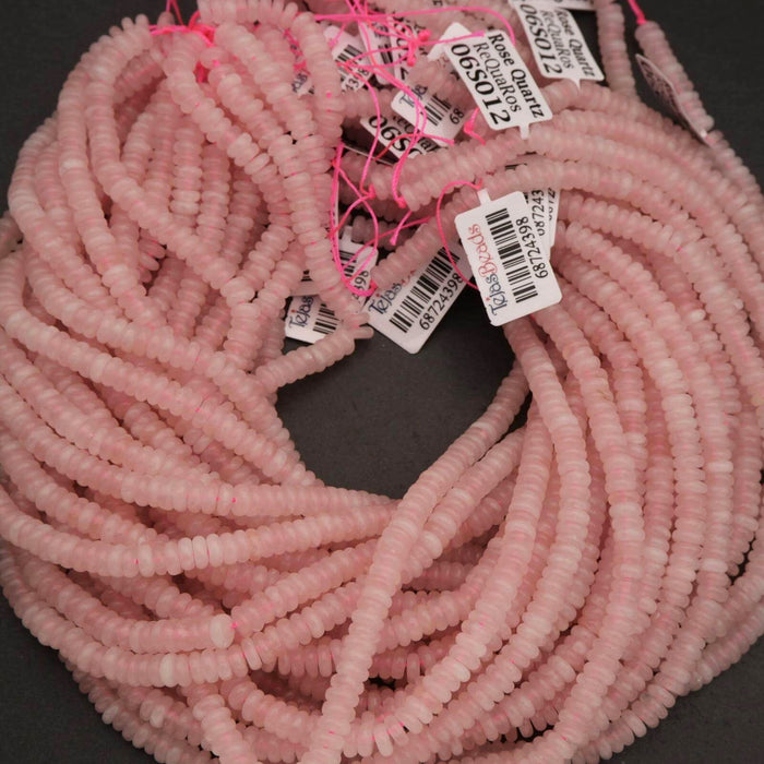 Pink beads with price tags on a dark surface