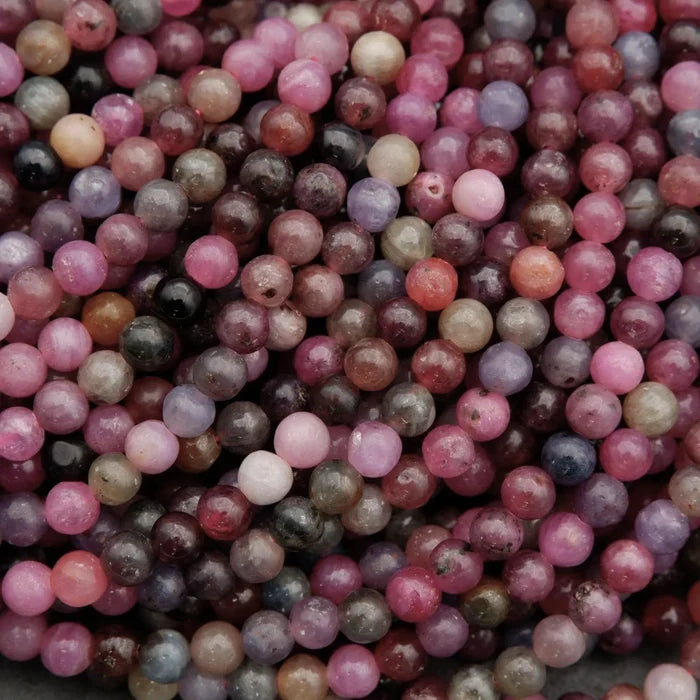 Natural ruby sapphire bead strands displaying shades of burgundy, blue, grey, and pink