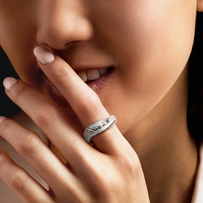 Sterling silver diamond-cut sculptural ring worn on finger, ridged band